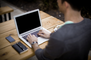 Man sitting at a desk typing on a MacBook Air